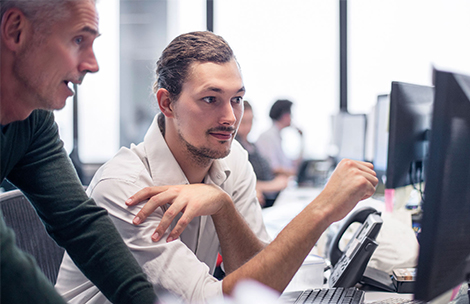 Zwei Männer schauen auf einen Bilschirm und unterhalten sich